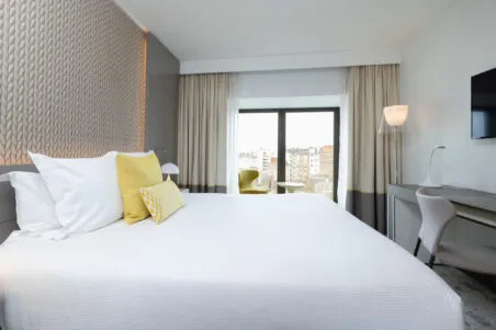 Wide view of an Executive room at the hotel with bed, desk and lounge area, in soft natural tones and a serene atmosphere.