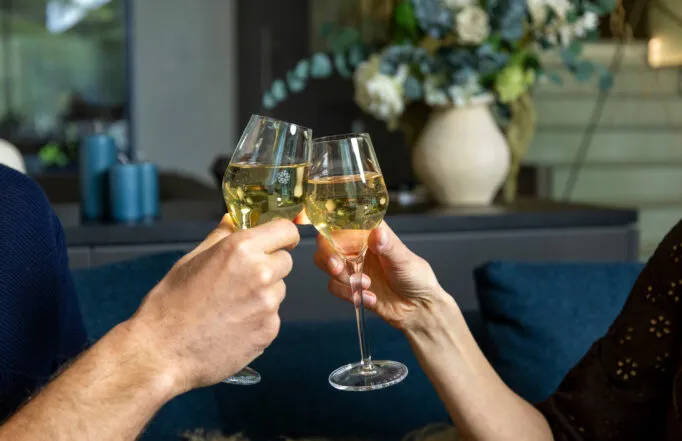 Close-up of a couple's hands toasting with champagne glasses in the hotel's bar lounge.