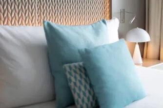 Close-up of the headboard and designer bedside table in the hotel room, with blue pillows and cushions, for a luxurious and comfortable feel.