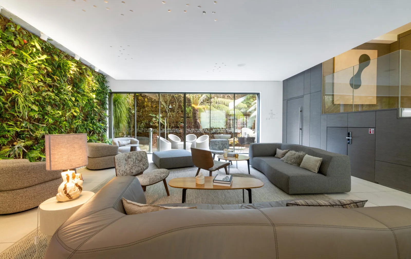 Vue d'ensemble du lobby de l'hôtel, avec canapé confortables et vue sur patio extérieur.