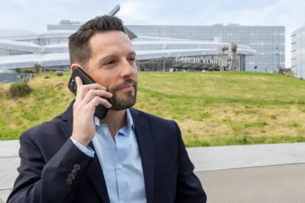 Visage d’un homme d’affaires au téléphone, avec la gare de Rennes en arrière-plan.