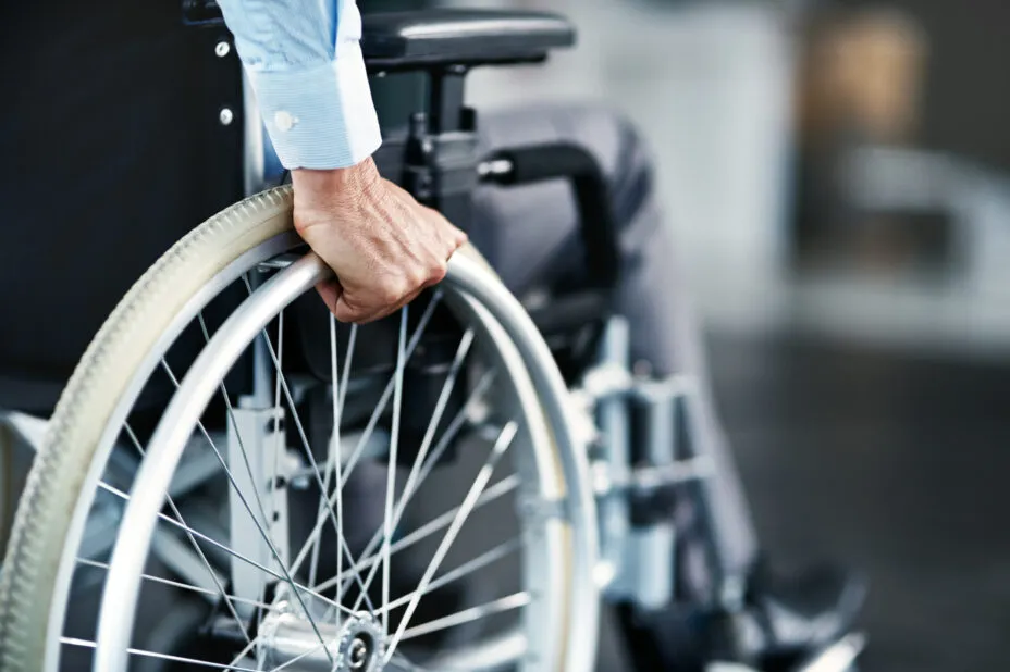 Gros plan sur la roue d’un fauteuil roulant avec la main d’un homme en situation de handicap dans l’hôtel.
