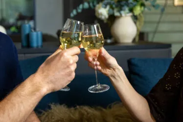 Gros plan sur des mains trinquant avec des coupes de champagne.
