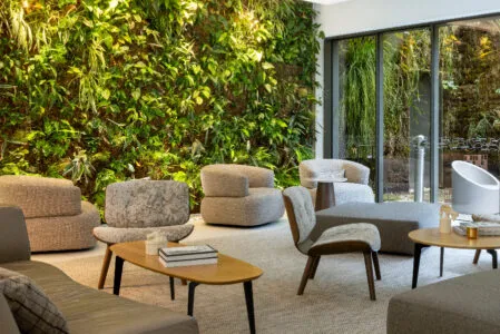 Wide view of the hotel's bar lounge seating areas with green wall and opening onto the outdoor patio.