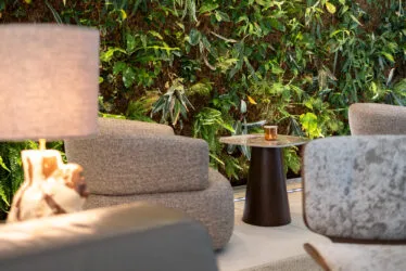 Close-up of one of the hotel's lounge areas with armchairs, a lit lamp and the green wall in the background.