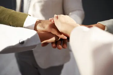 Gros plan sur les mains d’un groupe de personnes superposées, symbole d’unité et d’esprit d’équipe.
