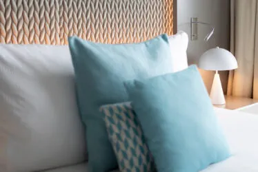 Gros plan sur la tête de lit matelassée d'une chambre Classique, avec oreillers et coussins bleus, ambiance luxe et confort.