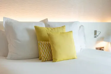 Gros plan sur la tête de lit rétroéclairée d’une chambre Deluxe de l’hôtel, mur texturé en tissu et ambiance raffinée.