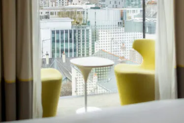 Salon en bow window d'une chambre Deluxe, avec de larges surfaces vitrées offrant une vue à 180 degrés sur la ville.