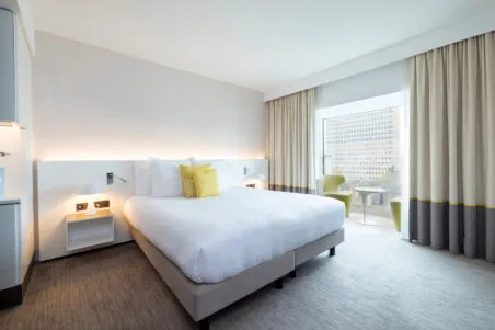 Vue d’ensemble d'une chambre Deluxe de l’hôtel avec coin salon en bow window, espaces généreux et luminosité.