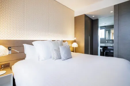 Vue de la suite Saint‑Antoine avec lit king size au premier plan et salle de bains visible en arrière‑plan.