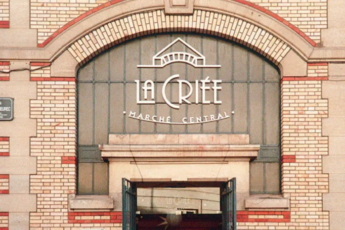 Façade en briques jaunes et rouge de La Criée, le marché central de Rennes, avec enseigne au-dessus de l’entrée.