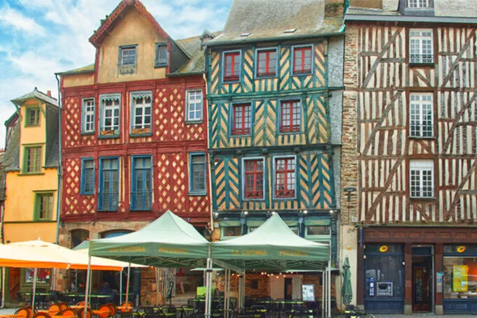 Bar and restaurant terraces on a pedestrian square with half-timbered buildings painted in bright colors.