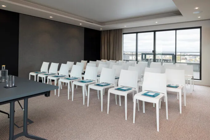 Salle de séminaire de l’hôtel vide, aménagée en configuration conférence avant l'arrivée de participants.