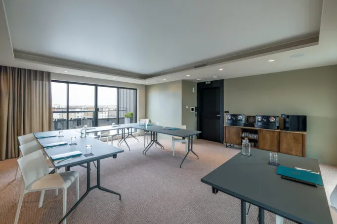 Salle de séminaire de l’hôtel vide, préparée en configuration en U pour accueillir des participants.