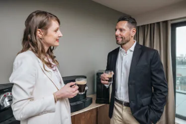 A man and a woman having coffee in the coffee corner of the hotel's seminar room.