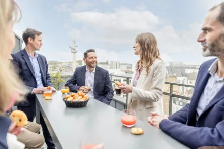 Group of professionals taking a break on the hotel's terrace with coffee and pastries during a seminar.
