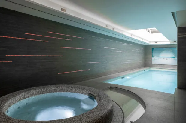 The wellness area, with the jacuzzi in the foreground and the light-filled pool in the background.