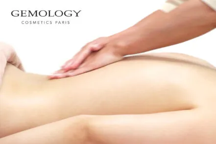 Gros plan sur le dos d'une femme allongée, sur qui une praticienne du spa effectue une soin du corps.