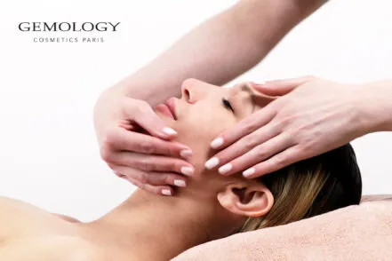 Gros plan sur le visage d'une femme allongée, sur qui une praticienne du spa effectue une soin du visage.