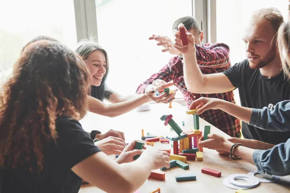 Group of people around a hotel table, smiling and playing an agility game with wooden pieces.