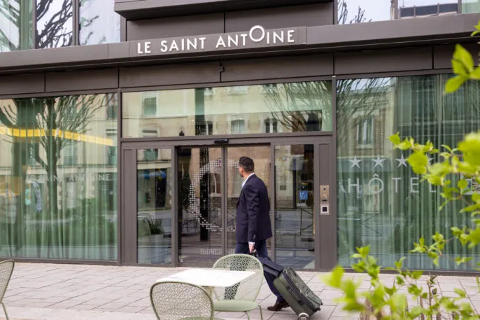 Businessman arriving in front of the hotel in the street with a rolling suitcase.